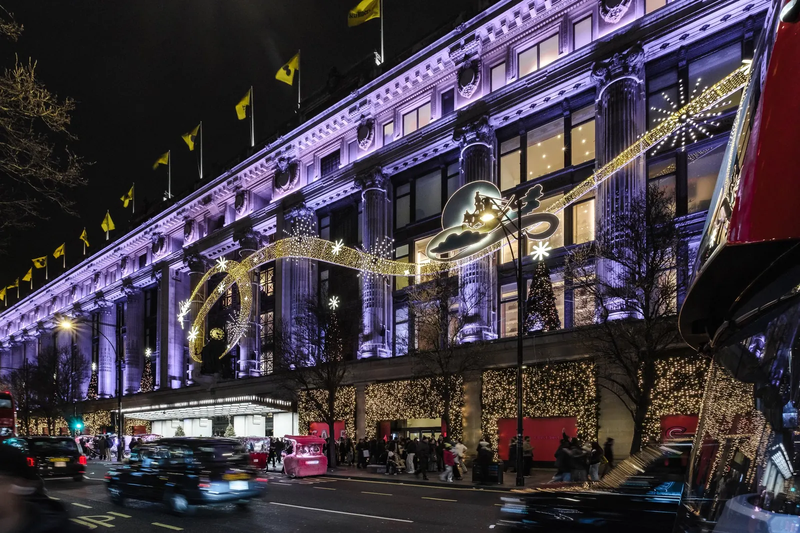 Selfridges on Oxford Street lit for Christmas, with black cabs passing