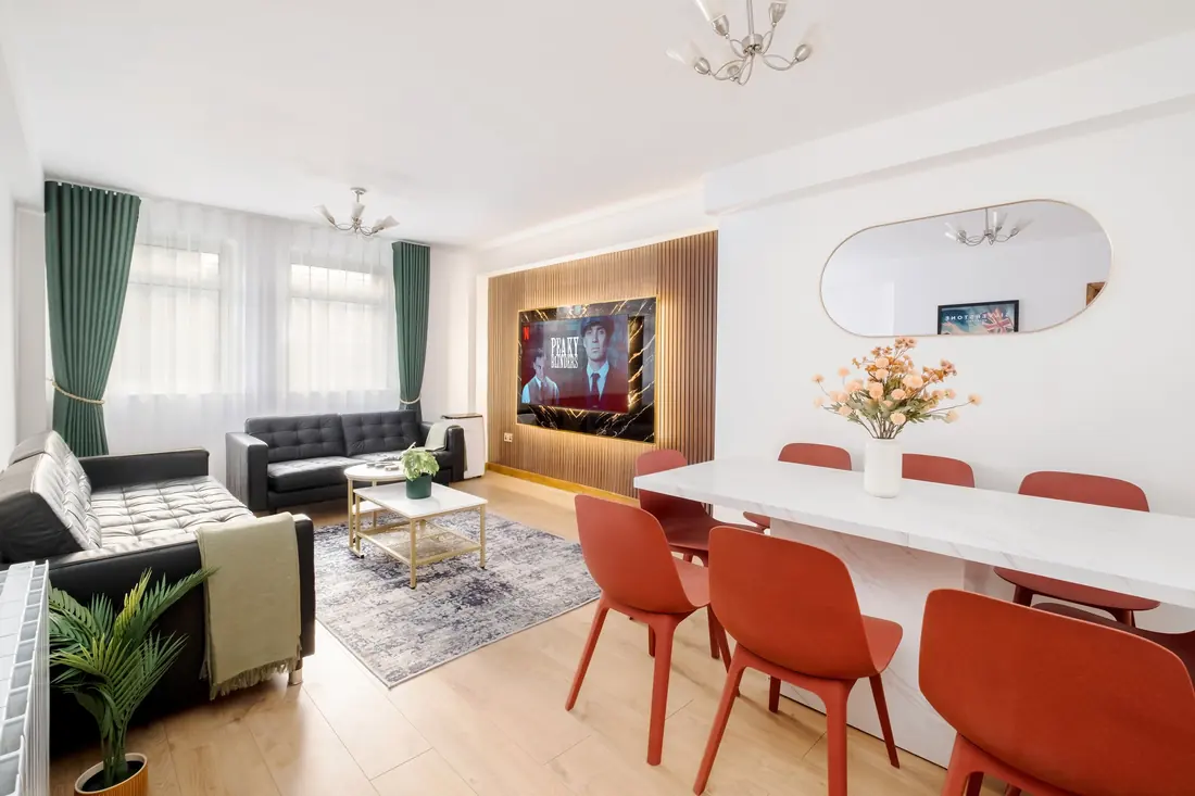Living room with black leather sofas, a white dining table and red chairs