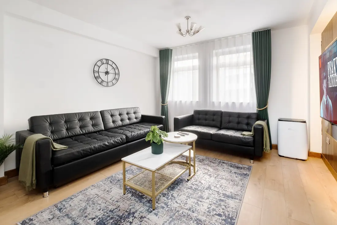 Sofas by the windows and their green curtains