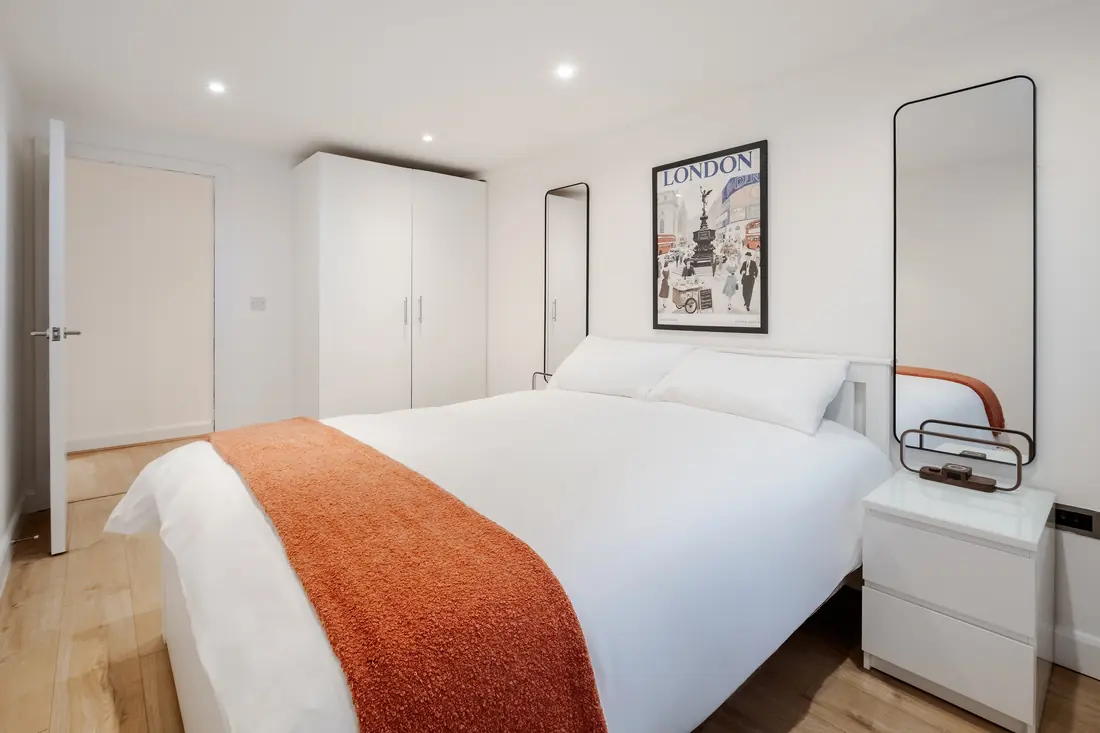 King bed with an orange throw and wardrobe