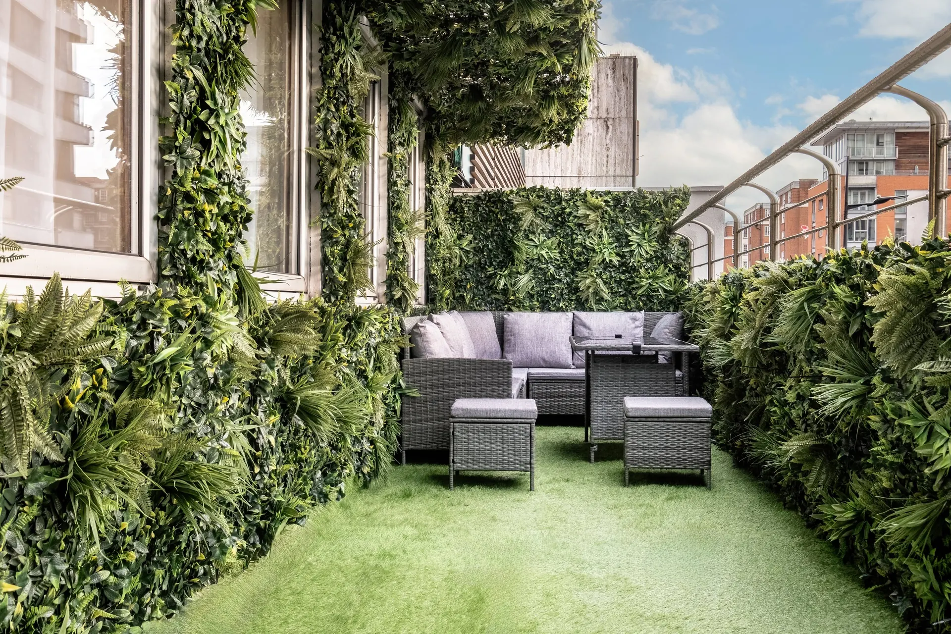 Private balcony with planted green walls, a lawn and outdoor sofas