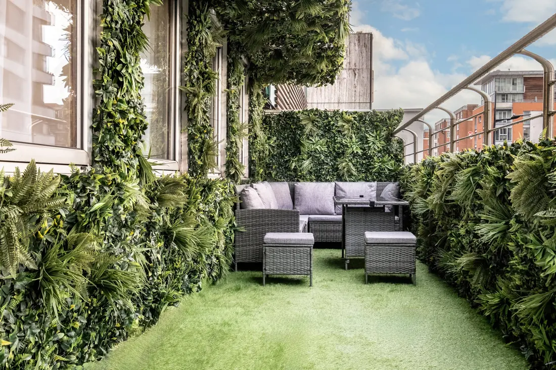 Private balcony with planted green walls, a lawn and outdoor sofas